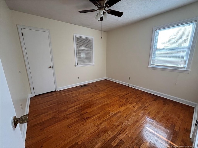unfurnished bedroom with wood finished floors, visible vents, baseboards, and ceiling fan