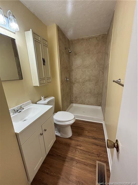 bathroom featuring visible vents, wood finished floors, a textured ceiling, and toilet