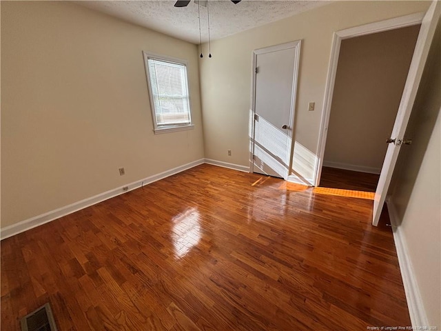 unfurnished bedroom with wood finished floors, a textured ceiling, baseboards, and visible vents