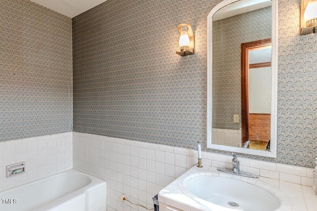 full bathroom with vanity, a garden tub, wallpapered walls, and tile walls