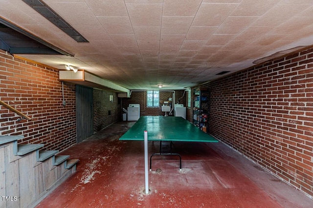 playroom featuring brick wall, concrete flooring, and washer / clothes dryer