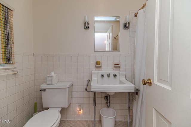 bathroom featuring a sink, tile patterned flooring, toilet, a wainscoted wall, and tile walls