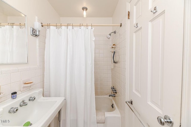 bathroom with a sink, tile walls, and shower / tub combo with curtain