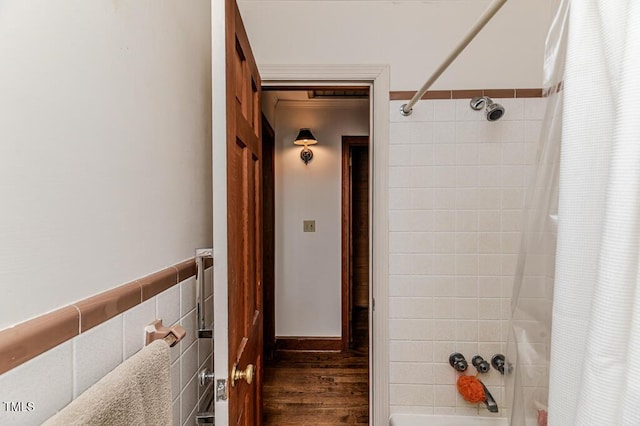 full bath featuring tile walls, wood finished floors, and shower / tub combo