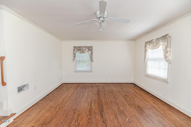 spare room featuring a ceiling fan, baseboards, wood finished floors, visible vents, and ornamental molding