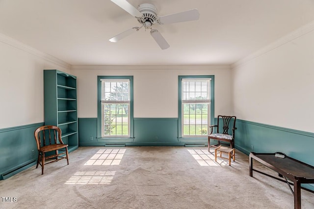 living area featuring wainscoting, ornamental molding, and a healthy amount of sunlight