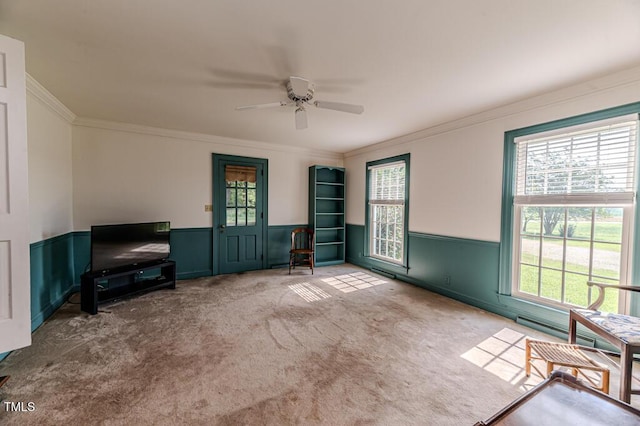 interior space featuring a wainscoted wall, ornamental molding, carpet, and ceiling fan