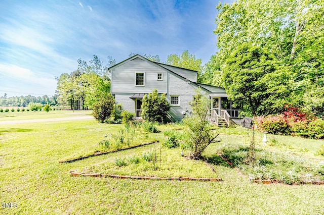 view of home's exterior with a sunroom and a yard