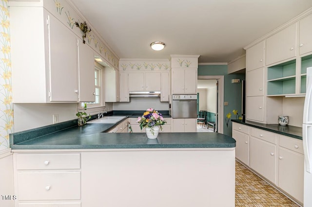 kitchen featuring dark countertops, a sink, a peninsula, wall oven, and under cabinet range hood