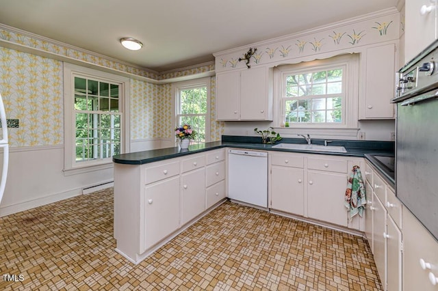 kitchen featuring a peninsula, white dishwasher, a baseboard radiator, wallpapered walls, and a sink