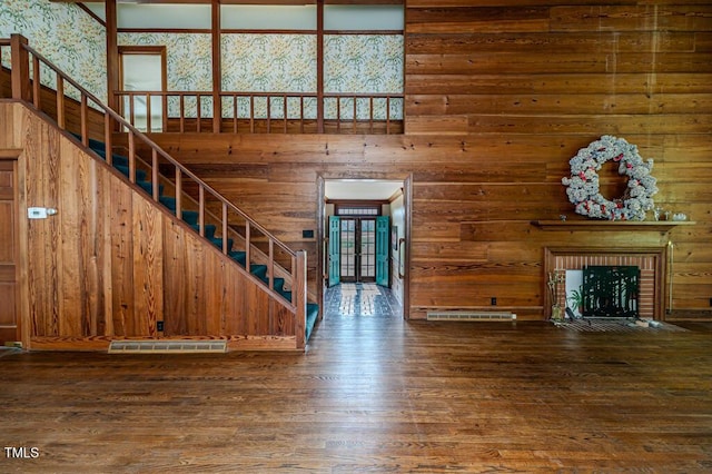unfurnished living room featuring wood walls, french doors, wood finished floors, visible vents, and stairway