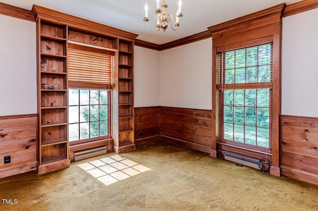 spare room with carpet floors, a chandelier, a baseboard heating unit, and wainscoting