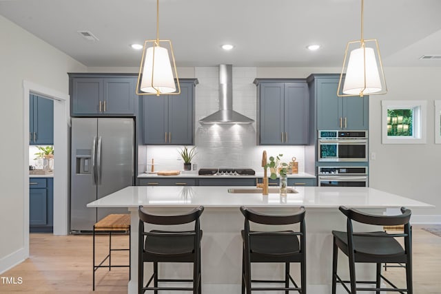 kitchen featuring decorative backsplash, visible vents, appliances with stainless steel finishes, light countertops, and wall chimney exhaust hood