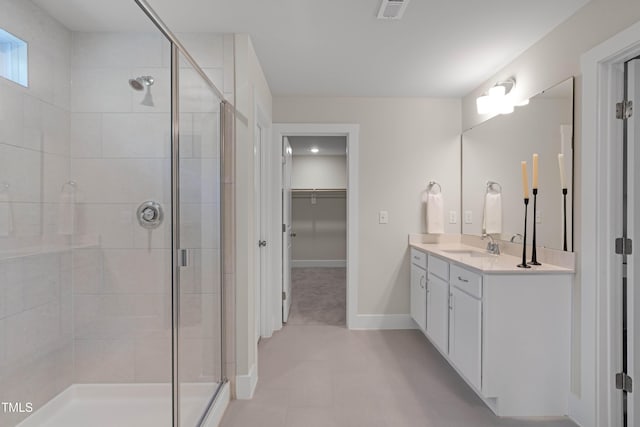 bathroom with vanity, a walk in closet, a stall shower, and visible vents