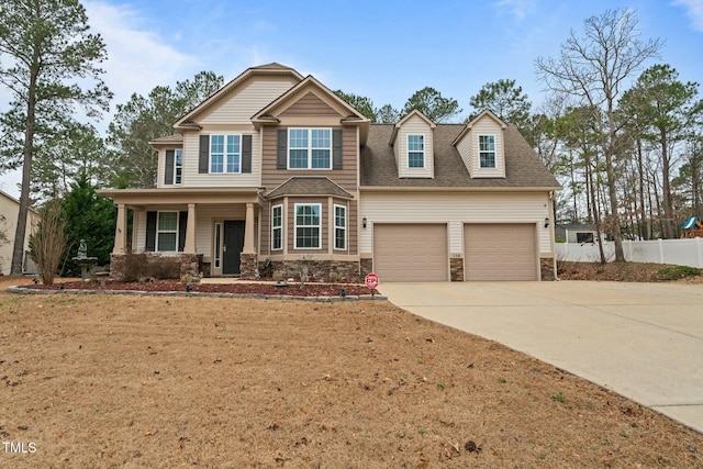 craftsman house featuring fence, stone siding, concrete driveway, and a porch
