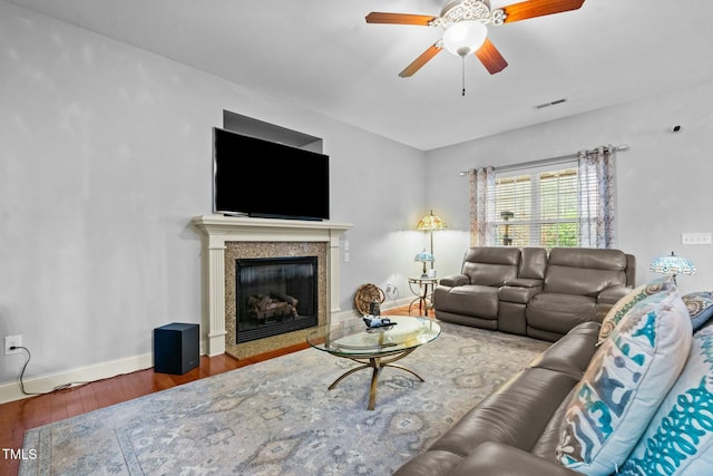 living room with ceiling fan, wood finished floors, a high end fireplace, and baseboards
