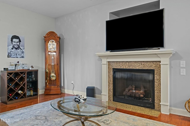 living area with wood finished floors, a high end fireplace, and baseboards