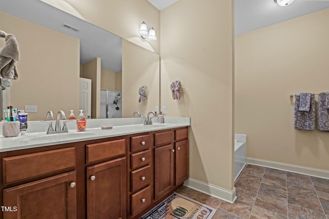 full bathroom featuring baseboards, double vanity, a shower with shower door, a bathtub, and stone finish floors
