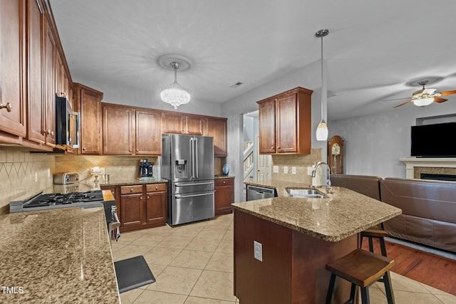 kitchen featuring appliances with stainless steel finishes, a sink, open floor plan, a breakfast bar area, and a peninsula