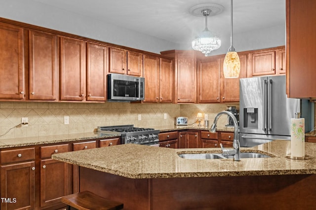 kitchen featuring appliances with stainless steel finishes, a sink, light stone countertops, pendant lighting, and tasteful backsplash
