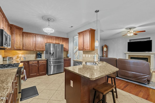 kitchen with stainless steel appliances, a sink, open floor plan, light tile patterned flooring, and a kitchen breakfast bar