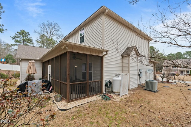 rear view of house with a sunroom, a ceiling fan, central AC unit, and roof with shingles