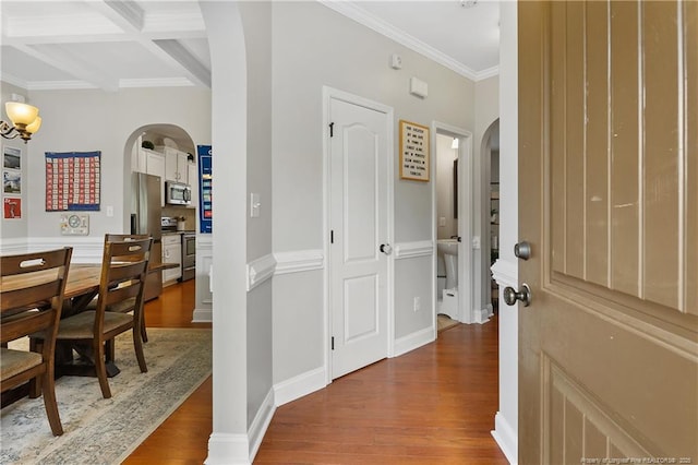 foyer entrance featuring arched walkways, wood finished floors, ornamental molding, beam ceiling, and coffered ceiling