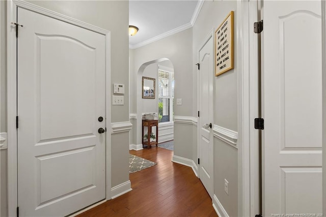 entryway featuring arched walkways, crown molding, and dark wood finished floors