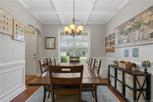 dining space featuring arched walkways, wood finished floors, coffered ceiling, a chandelier, and beamed ceiling