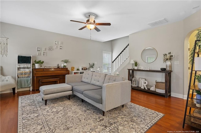 living room with arched walkways, ceiling fan, wood finished floors, and stairs