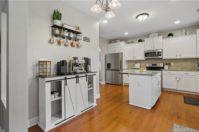 kitchen with stainless steel appliances, a center island, white cabinets, decorative backsplash, and recessed lighting