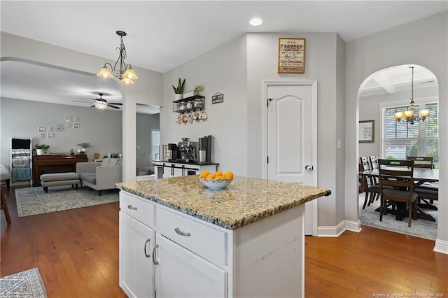 kitchen featuring a chandelier, a ceiling fan, arched walkways, white cabinets, and dark wood-style flooring