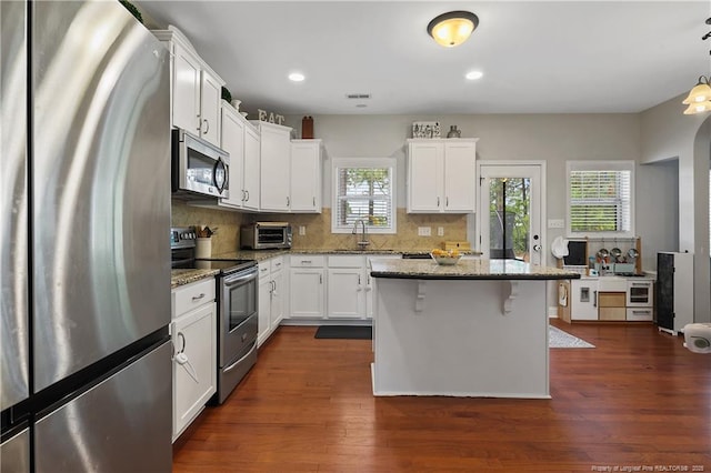 kitchen with appliances with stainless steel finishes, a sink, light stone countertops, white cabinets, and recessed lighting