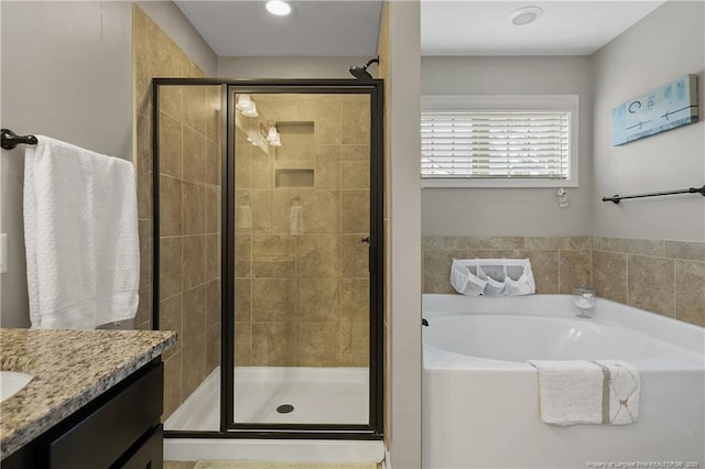 bathroom with a shower stall, a bath, and vanity