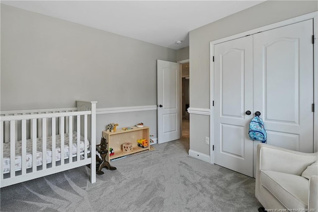 carpeted bedroom featuring a crib and a closet