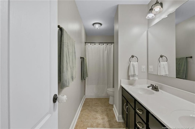 bathroom featuring baseboards, toilet, double vanity, and curtained shower