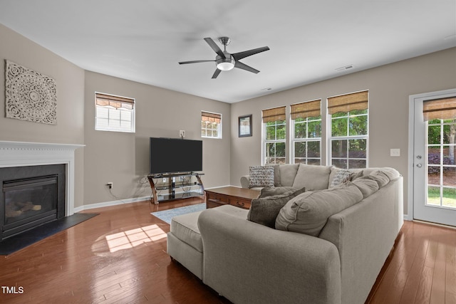 living room with wood-type flooring, visible vents, a fireplace with flush hearth, and a wealth of natural light