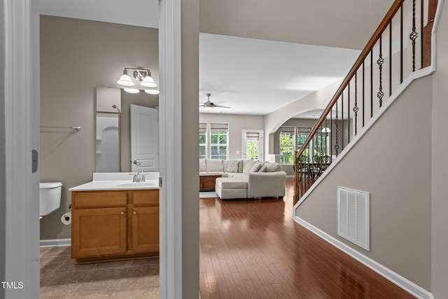 bathroom with visible vents, wood-type flooring, vanity, baseboards, and a ceiling fan