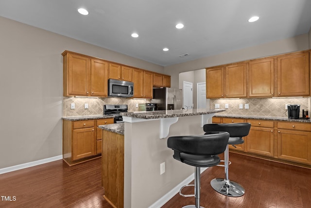 kitchen with a breakfast bar area, dark wood-style flooring, baseboards, and appliances with stainless steel finishes