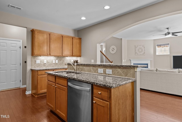 kitchen with visible vents, dishwasher, dark stone counters, a sink, and backsplash