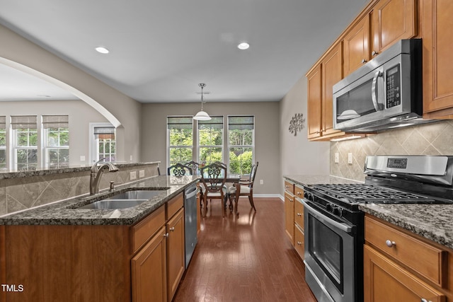 kitchen featuring brown cabinets, stainless steel appliances, a healthy amount of sunlight, and a sink