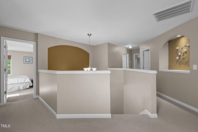 hallway featuring baseboards, carpet, an upstairs landing, and visible vents