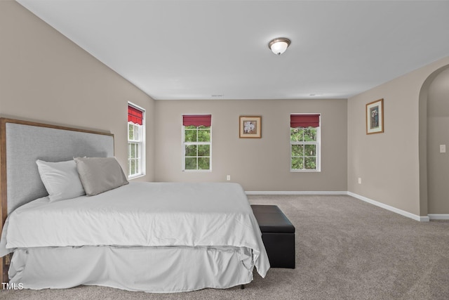 bedroom with baseboards, arched walkways, and carpet floors