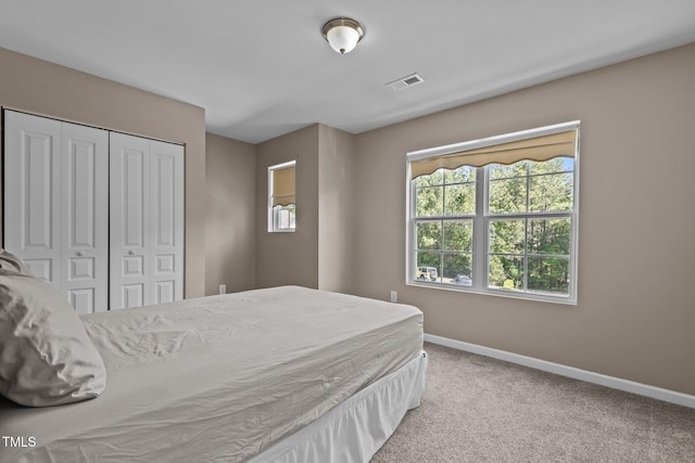 carpeted bedroom with baseboards, visible vents, multiple windows, and a closet