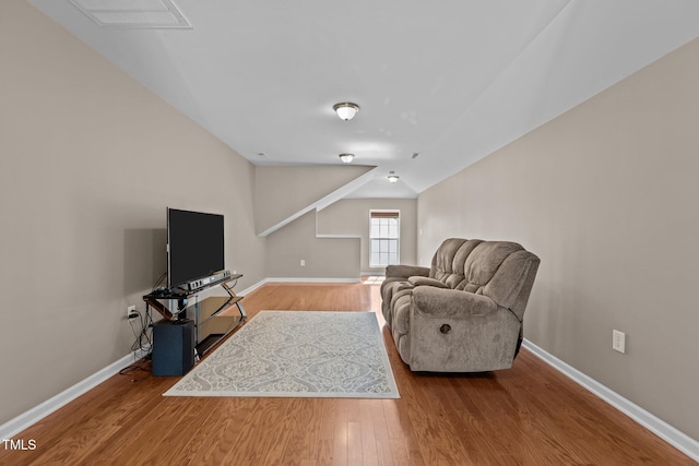 sitting room with baseboards, vaulted ceiling, wood finished floors, and visible vents