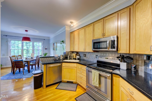 kitchen with a peninsula, light brown cabinetry, light wood-type flooring, a sink, and stainless steel appliances