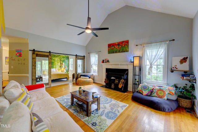 living room featuring a ceiling fan, wood finished floors, a healthy amount of sunlight, and high vaulted ceiling