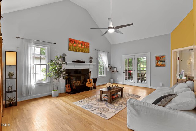 6 Chelan Ct, Durham, NC 27713 - living area featuring high vaulted ceiling, a glass covered fireplace, ceiling fan, wood finished floors, and healthy amount of natural light