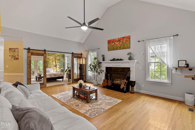 6 Chelan Ct, Durham, NC 27713 - living room with a barn door, a ceiling fan, high vaulted ceiling, wood finished floors, and a glass covered fireplace