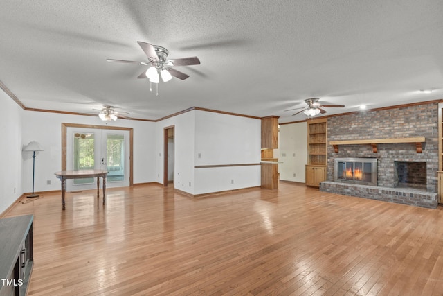 unfurnished living room with a fireplace, baseboards, a textured ceiling, a ceiling fan, and light wood finished floors